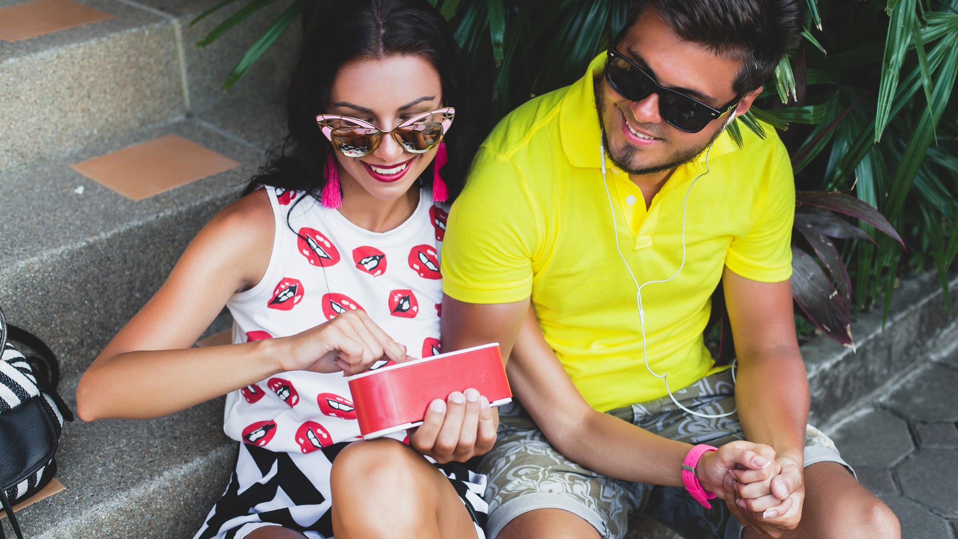 Pareja usando merchandising para eventos de verano con altavoz portátil personalizado